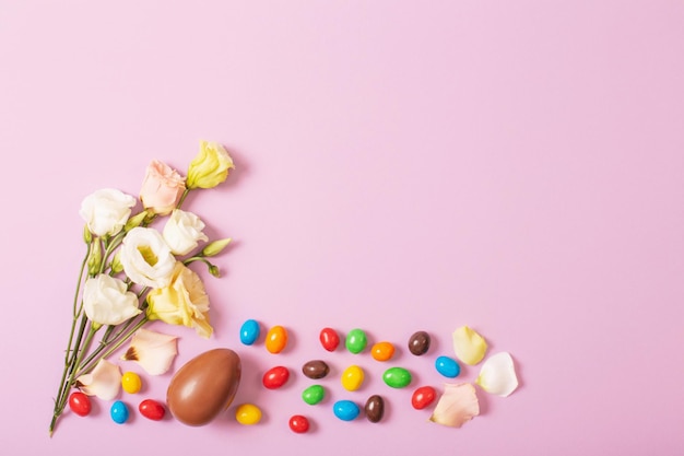 Huevos de chocolate de Pascua y flores sobre fondo de papel de color