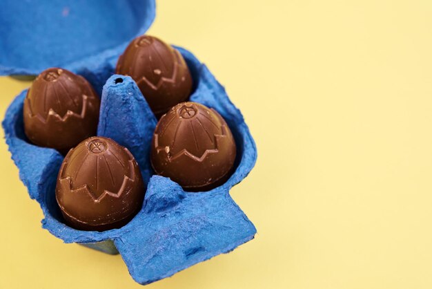 Huevos de chocolate en soporte de caja sobre fondo amarillo