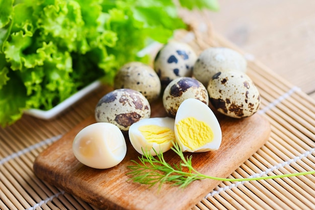 Huevos cocidos comida huevos de codorniz en plato de madera huevos de desayuno con huevos de codorniz frescos y lechuga vegetal eneldo en el fondo de la mesa