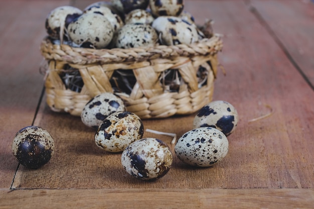 Huevos de codornices en la cesta de bambú en el viejo fondo de madera de la tabla.