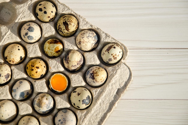 Huevos de codorniz en una caja de cartón textura de primer plano bandeja de huevos ecológica Un huevo está roto