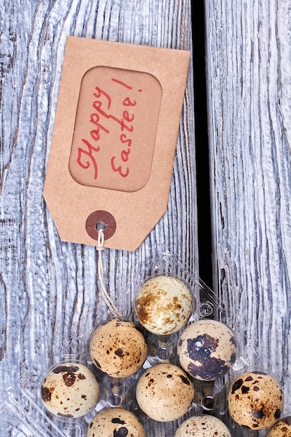 Foto huevos de codorniz en caja de plástico etiqueta de saludo en huevos cálidos deseos para pascua