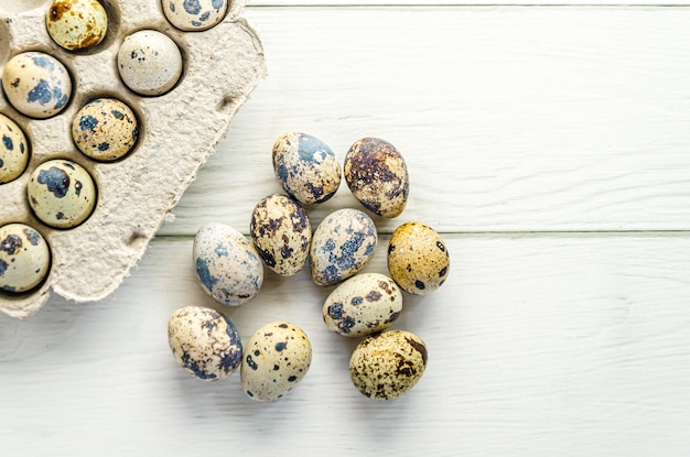 Huevos de codorniz colocados sobre una mesa de madera blanca cerca de una bandeja de cartón Embalaje ecológico Productos agrícolas