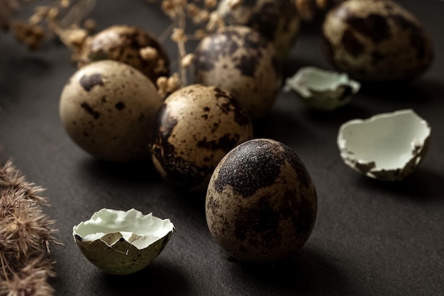 Huevos de codorniz manchados y trozos de cáscara de huevo esparcidos en la superficie de la mesa, feliz decoración navideña de Pascua