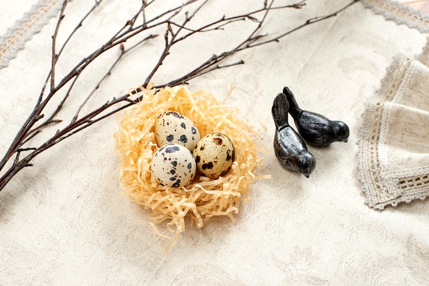 Huevos de codorniz de Pascua en un nido y ramas de sauce sobre un fondo claro