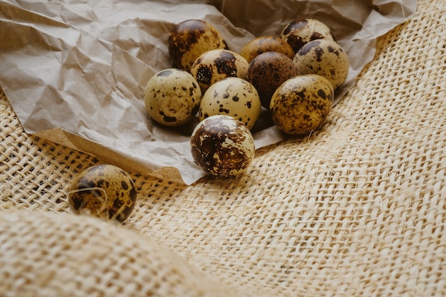 Huevos de codorniz de Pascua en papel artesanal y fondo de arpillera rústica Procesamiento de fotos antiguas