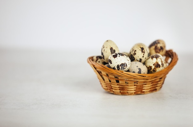 Foto huevos de codorniz en una pequeña cesta sobre un fondo blanco.