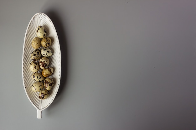 Huevos de codorniz en un plato en forma de hoja, minimalismo. elegante fondo de Pascua, lugar para texto, espacio de copia.