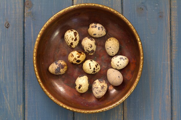 Huevos de codorniz en plato sobre fondo azul.