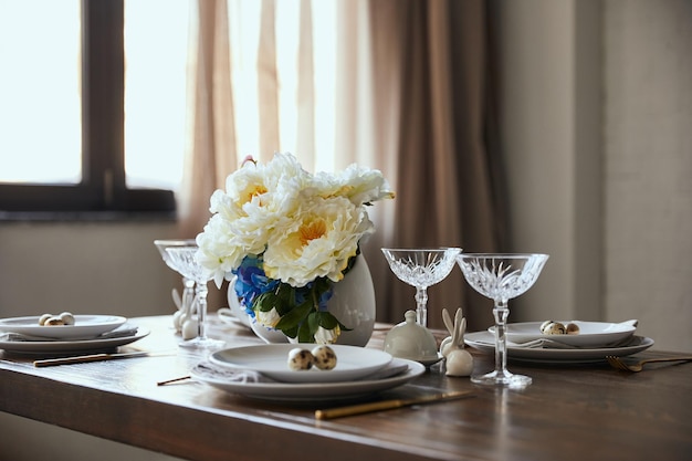 huevos de codorniz en platos blancos flores en jarrones y vasos de cristal en la mesa de madera en casa