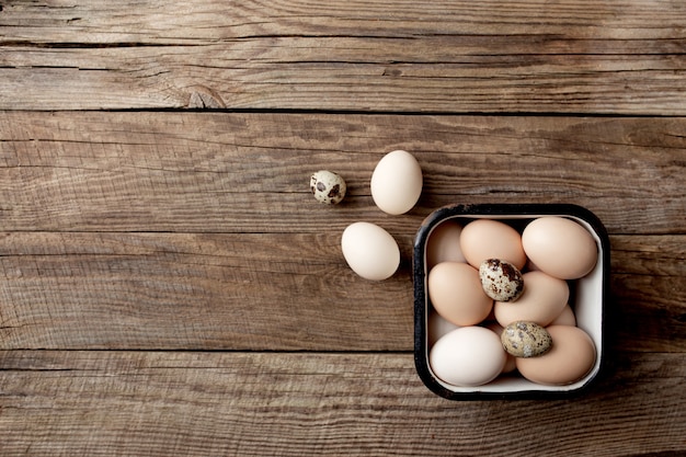 Huevos de codorniz y pollo orgánicos en caja de metal sobre fondo de madera. Concepto de hogar orgánico con huevos de gallinas criadas en libertad y en pasto