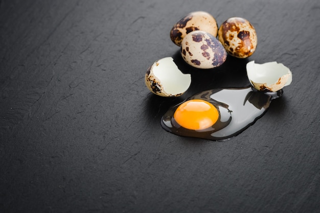Huevos de codorniz sobre fondo de piedra negra, huevo de codorniz roto, agrietado, yema de huevo de codorniz. Producto organico.