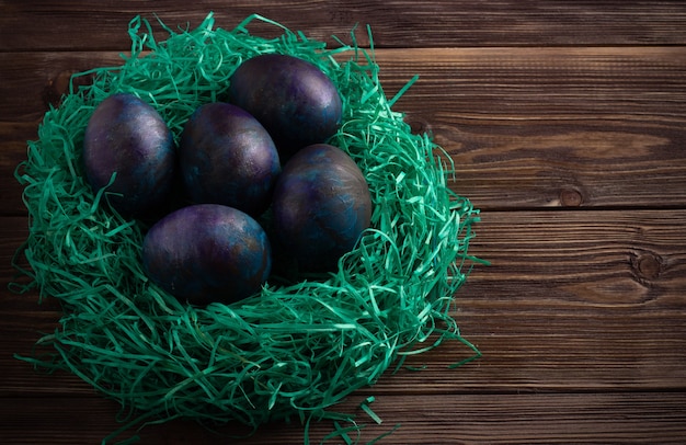 Foto huevos de colores en materiales ecológicos anidan en el estilo rústico de madera oscura