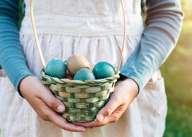 Foto huevos de colores rústicos de pascua en cesta de mimbre en manos de una mujer en concepto de vacaciones de tela de lino