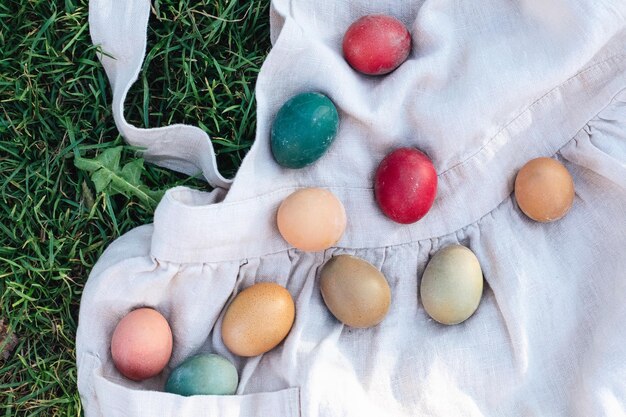 Foto huevos de colores rústicos de pascua en tela de lino sobre el fondo verde concepto de vacaciones de primavera