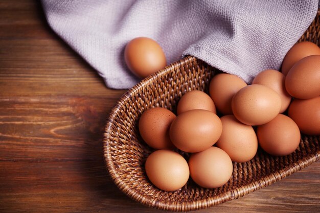 Huevos crudos en canasta sobre fondo de madera