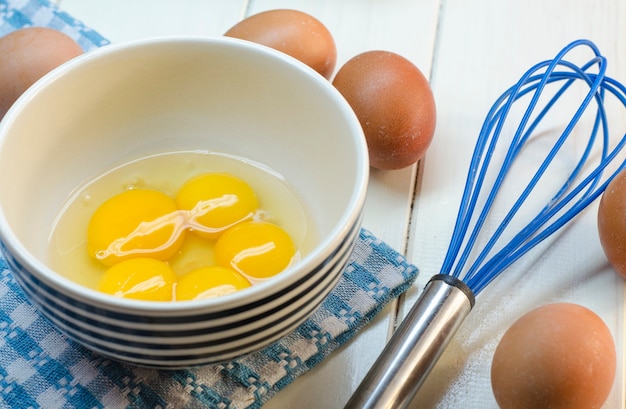 Huevos crudos y corola sobre una superficie blanca