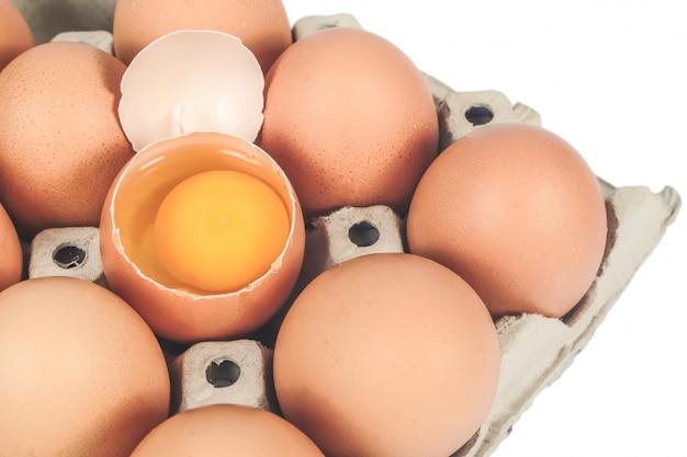 Huevos crudos del pollo en caja de huevo en el fondo blanco.