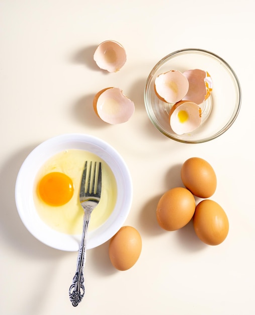 Huevos crudos en un recipiente de vidrio y blanco sobre la mesa Plano Fondo blanco roto