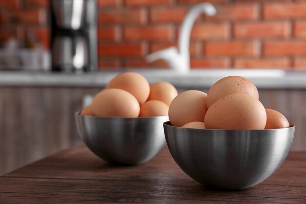 Huevos crudos en tazones sobre mesa de madera