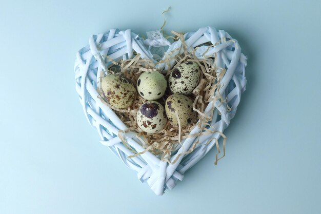 Huevos de decoración de Pascua en un corazón trenzado en una vista superior de fondo azul