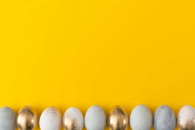 Huevos dorados y grises sobre un fondo amarillo Concepto mínimo de pascua