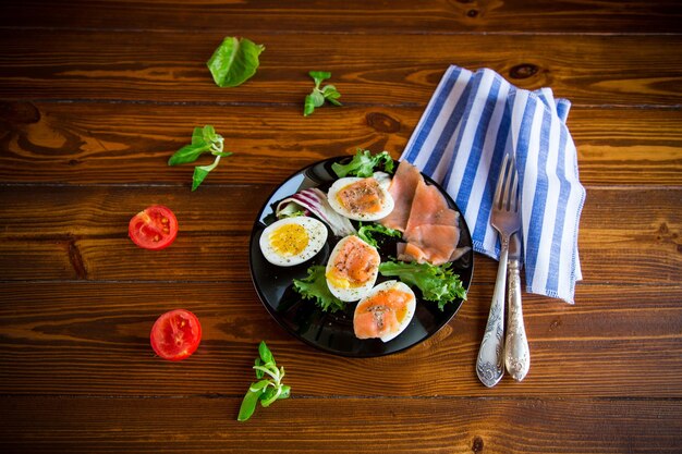 huevos duros con pescado rojo salado, hierbas y condimentos en un plato sobre una mesa de madera