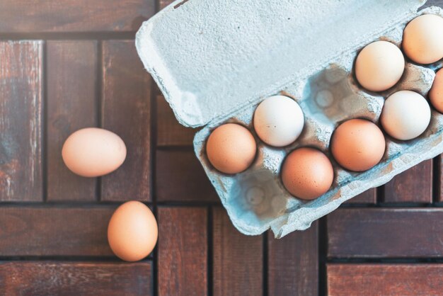 Huevos ecológicos en caja de cartón. Vista cercana de huevos de pollo crudos en suelo de madera