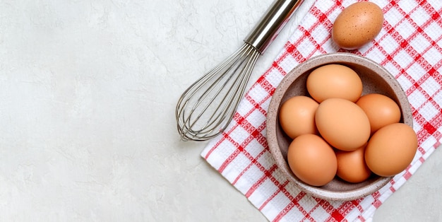 Huevos frescos en un batidor de tazón sobre un fondo claro Tema de cocina Vista superior con espacio de copia Banner