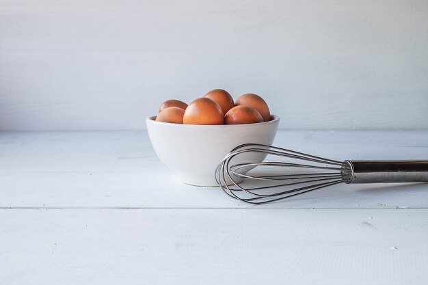 Huevos frescos para cocinar en una mesa de madera blanca
