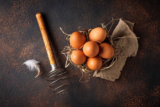 Huevos frescos de color marrón en un bol y batidor