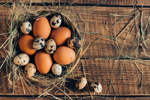 Huevos frescos y orgánicos. Vista superior de huevos marrones en un tazón con heno en mesa rústica de madera