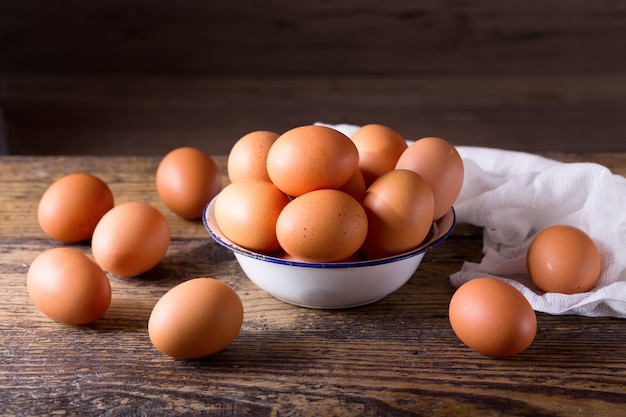 Huevos frescos en un recipiente sobre la mesa de madera