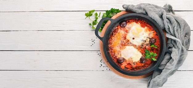 Huevos fritos fritos en una sartén con verduras y queso parmesano Sobre un fondo de madera Vista superior Espacio de copia