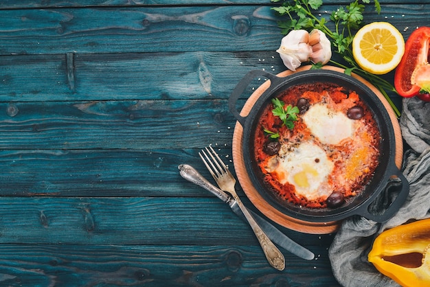 Huevos fritos fritos en una sartén con verduras y queso parmesano Sobre un fondo de madera Vista superior Espacio de copia