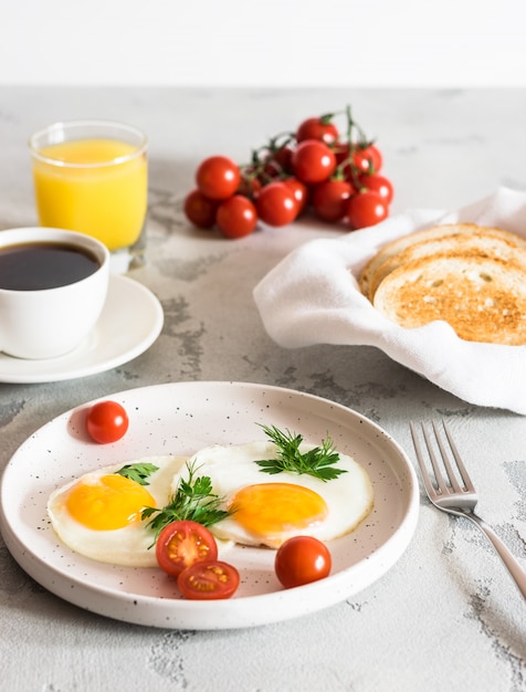 Huevos fritos con hierbas, tomates rojos, tostadas, café y jugo fresco