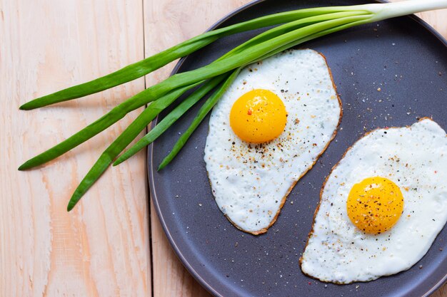 Huevos fritos en un plato con cebolla verde. Desayuno. Hermosa porción del plato. nutrición apropiada.