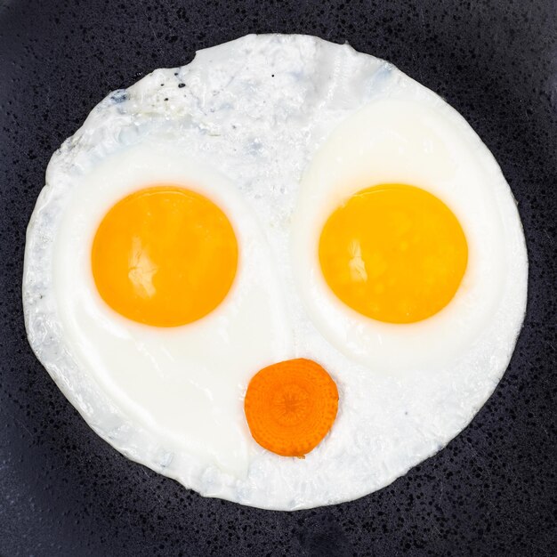 Huevos fritos y rodaja de zanahoria en un plato de cerca