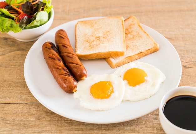 Huevos fritos con salchicha y pan.