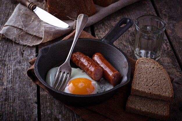 Huevos fritos con salchichas en una sartén.