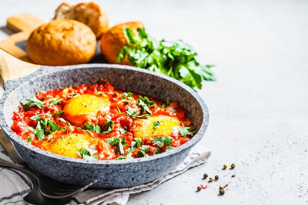 Huevos fritos en salsa de tomate con hierbas.