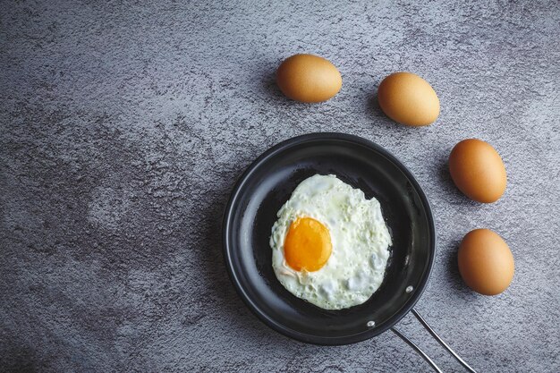 Huevos fritos en una sartén y huevos frescos sobre la mesa