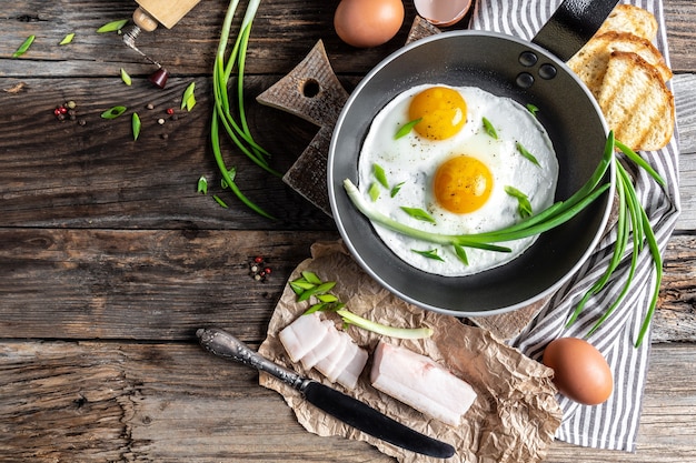 Huevos fritos en sartén con manteca de cerdo, pan y cebollas de plumas verdes