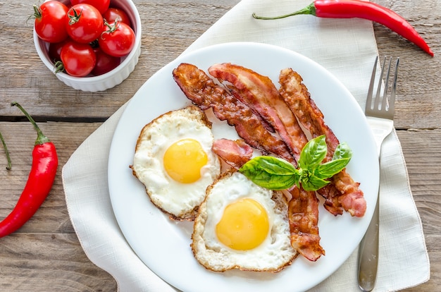 Huevos fritos con tocino en la mesa de madera