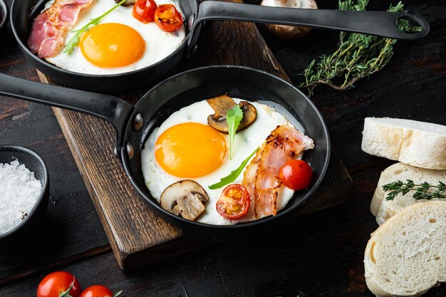 Huevos fritos con tocino y verduras en una sartén de hierro fundido, sobre la vieja mesa de madera oscura.