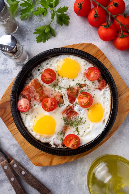 Huevos fritos, tocino y verduras en una sartén. Hora del desayuno. Vista superior.