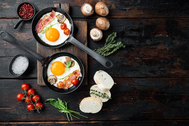 Huevos fritos con tomate cherry y pan para el desayuno en una sartén de hierro fundido, sobre el fondo de la vieja mesa de madera oscura, vista superior plana, con espacio para texto copyspace