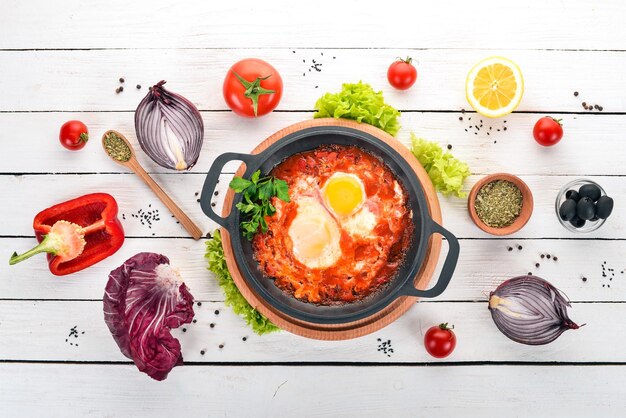 Huevos fritos con tomates y verduras frescas Sobre un fondo blanco de madera Vista superior Copiar espacio para el texto