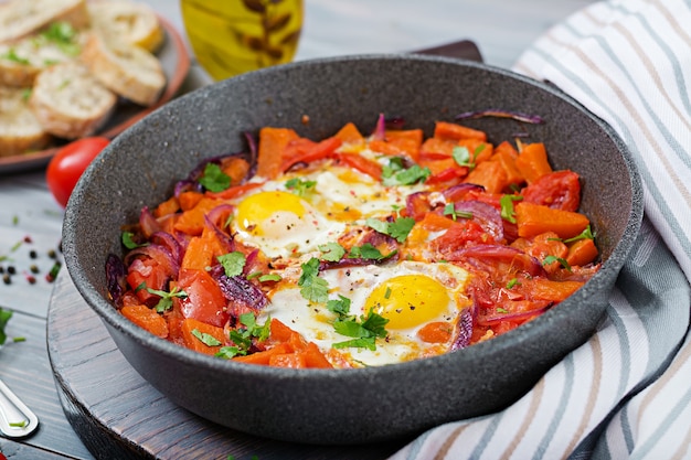 Huevos fritos con trozos de calabaza, cebollas rojas y tomates. Delicioso desayuno