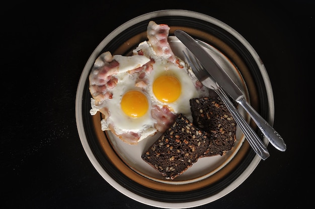 Huevos fritos con yema entera, tocino y tostadas - vista superior plana